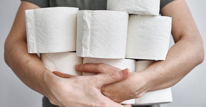 Mann hält viele WC-Papierrollen in den Armen, weil er Durchfall hat