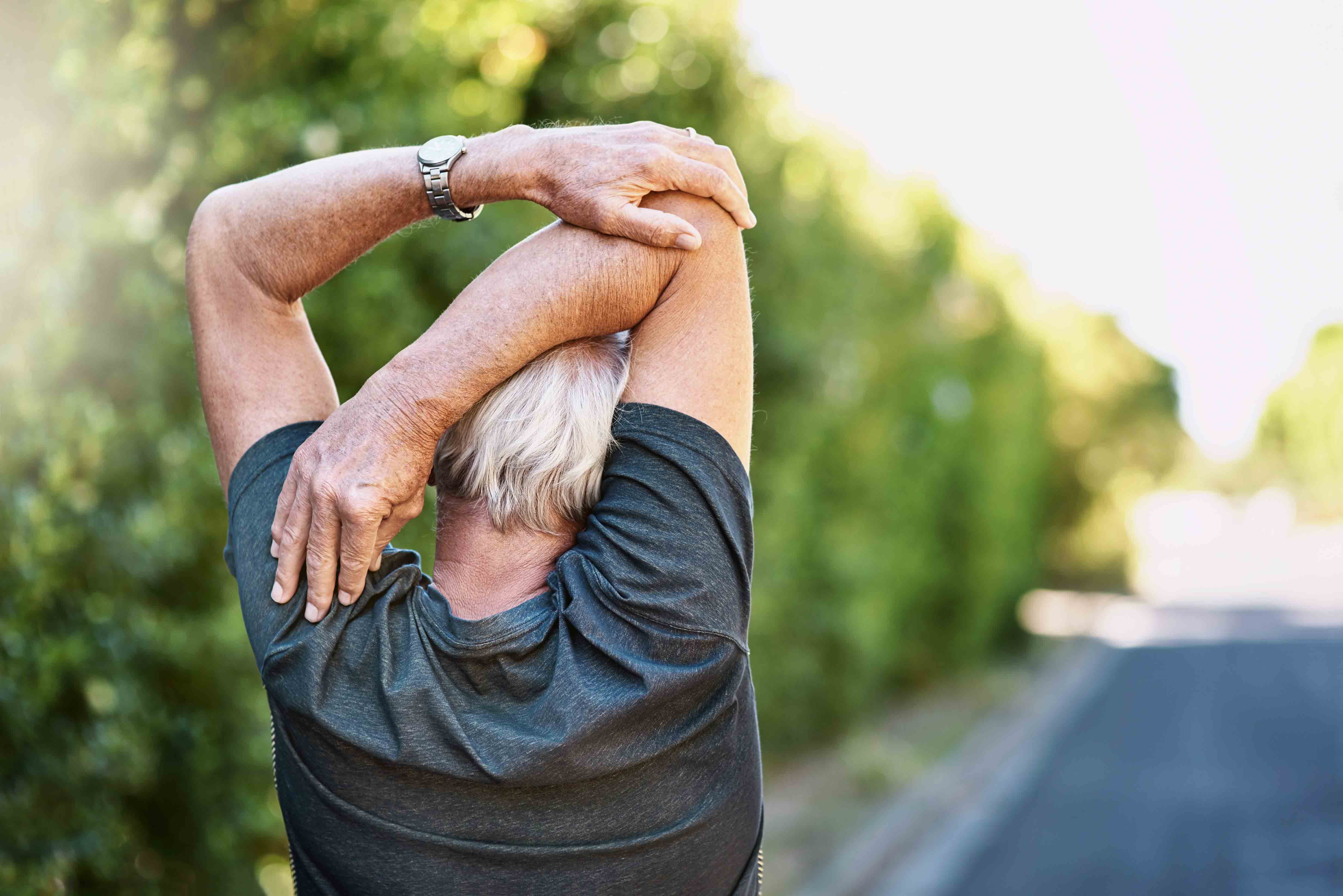 älterer Mann macht draussen Rückenübungen gegen Rückenschmerzen